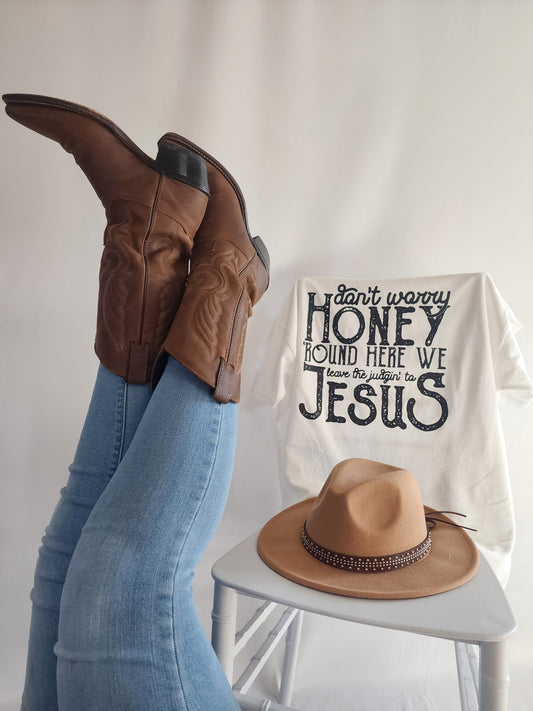 Don't Worry Honey white graphic tee styled with cowboy boots and tan hat on chair