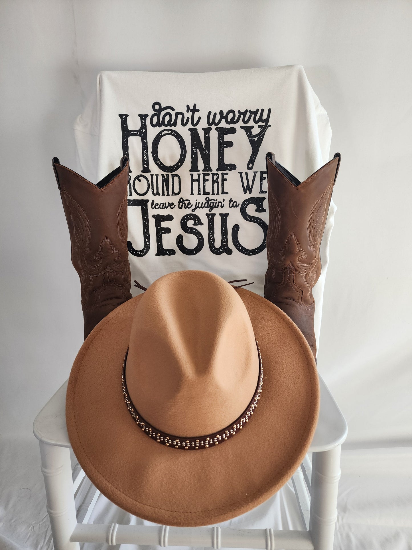 Close-up flat lay of Don't Worry Honey faith-based t-shirt with Western boots and hat