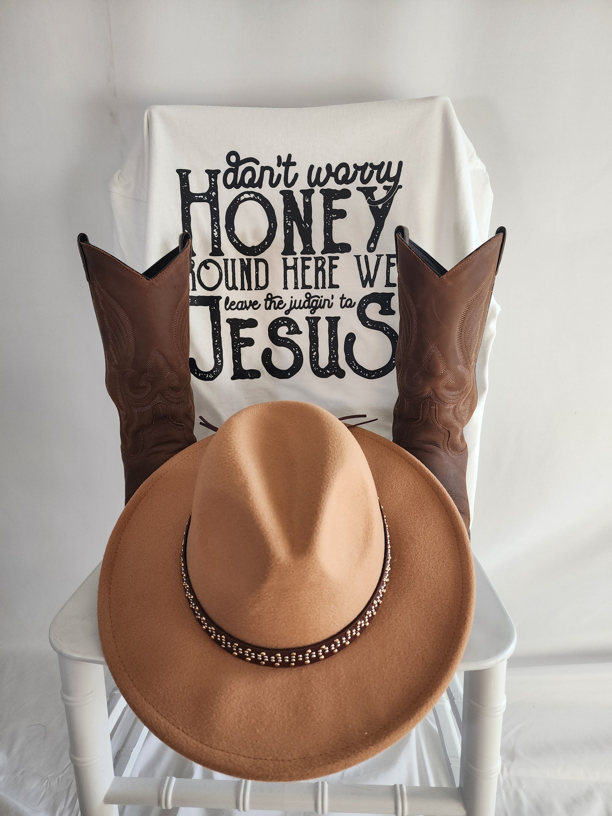 Close-up flat lay of Don't Worry Honey faith-based t-shirt with Western boots and hat