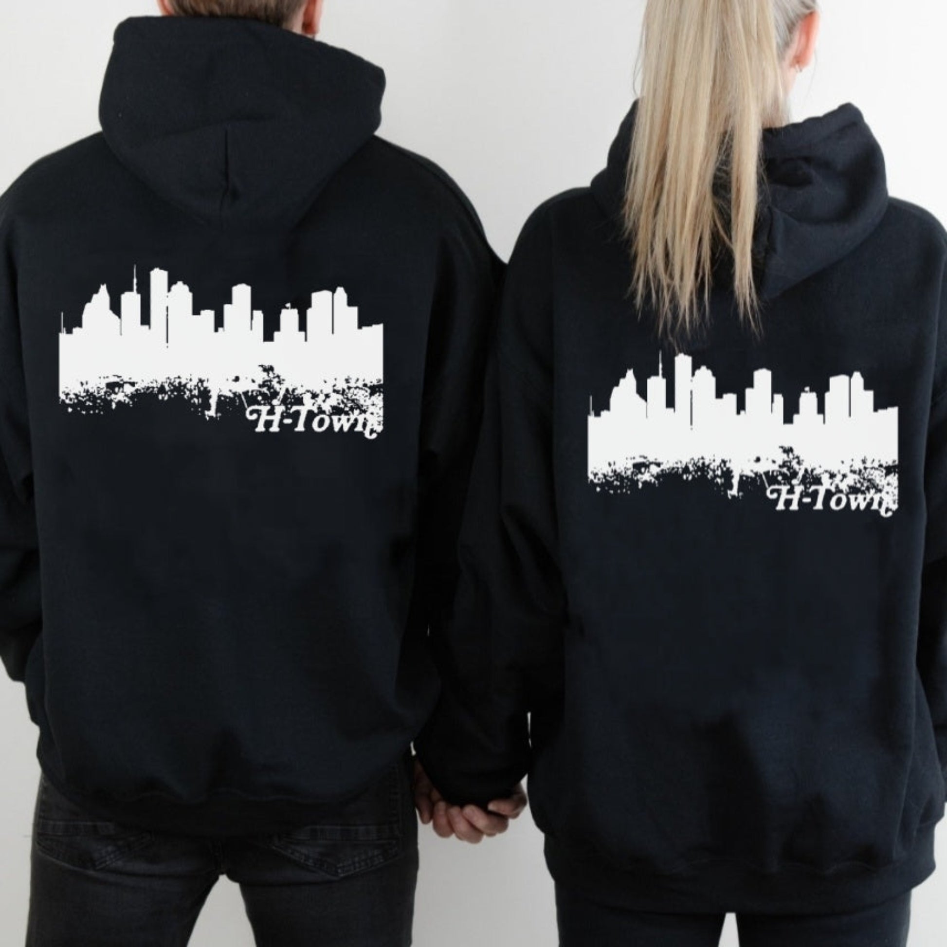 Back view of couple wearing black I've Witnessed It hoodies featuring Houston skyline design