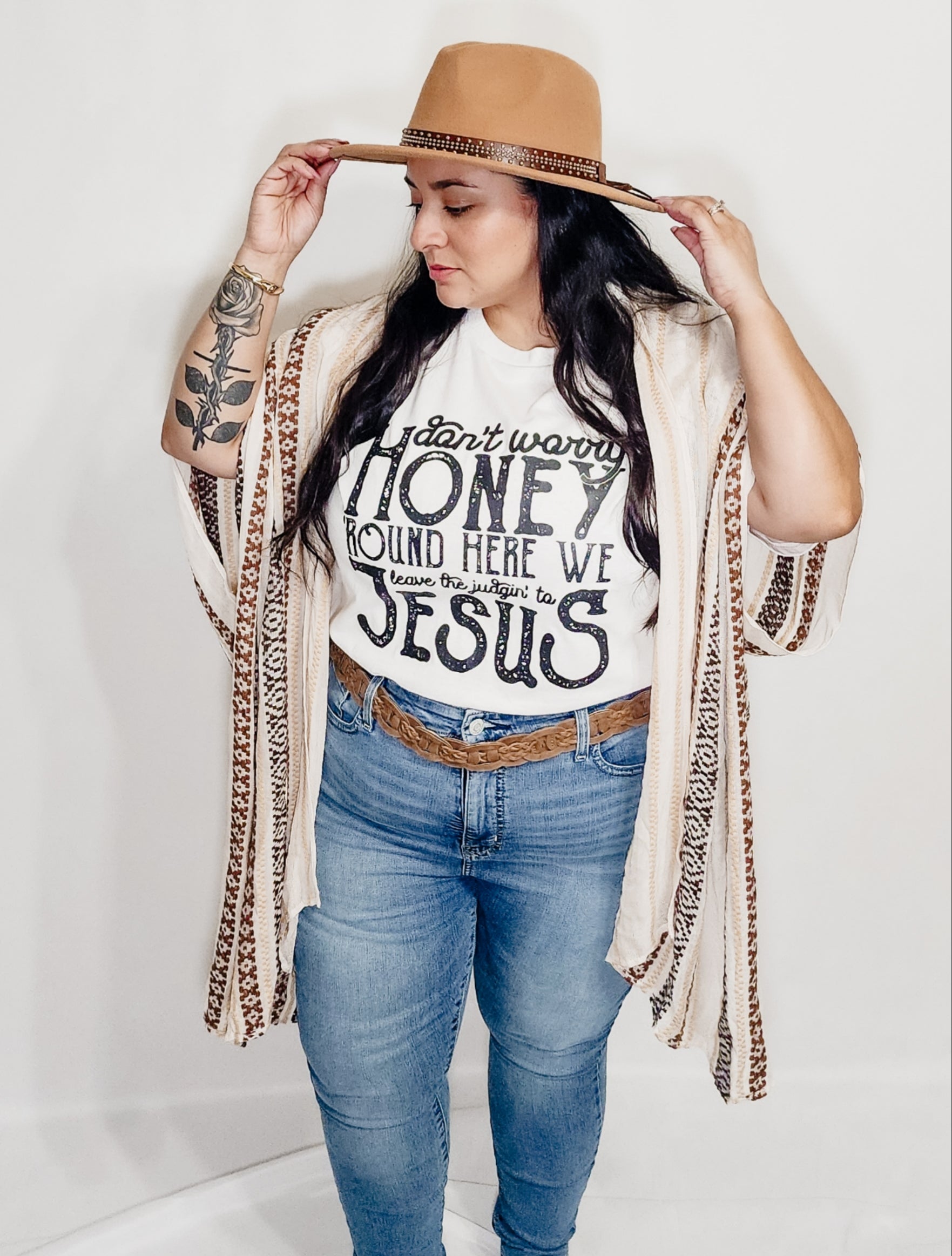 Woman modeling Don't Worry Honey tee with boho cardigan, jeans, and tan hat - full outfit styling