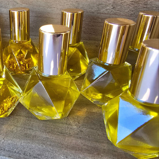 Collection of glass roller ball bottles filled with golden Exodus oil with a rustic wood background.