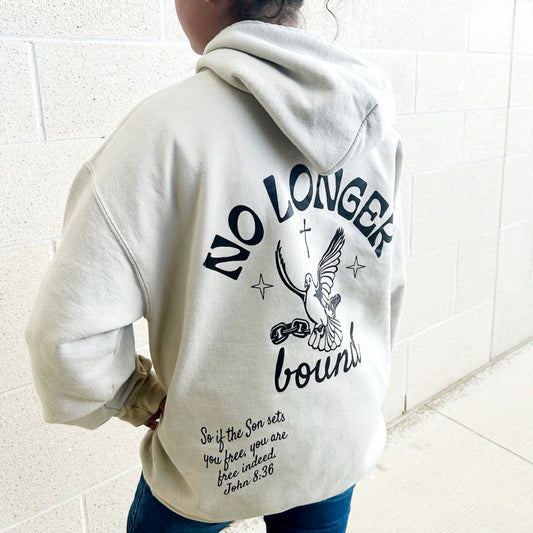 Teen wearing a hoodie with No Longer Bound text with an eagle design on the back, standing against a white tiled wall.